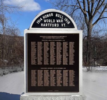 memorial wall of granite with large bronze plaques with names on both sides and curved capstone