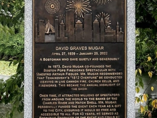 closeup of bronze plaque on granite pedestal surrounding by landscaping