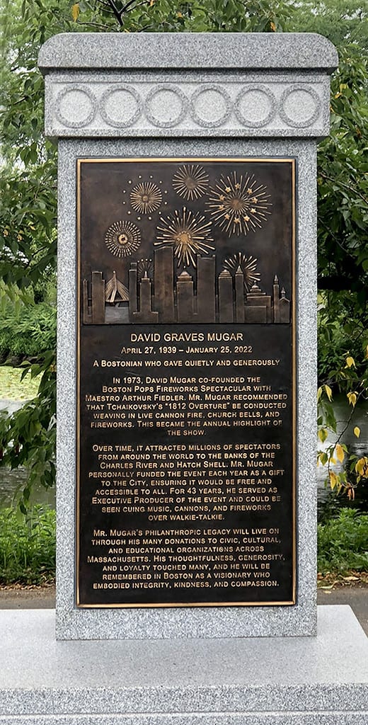 closeup of bronze plaque on granite pedestal surrounding by landscaping