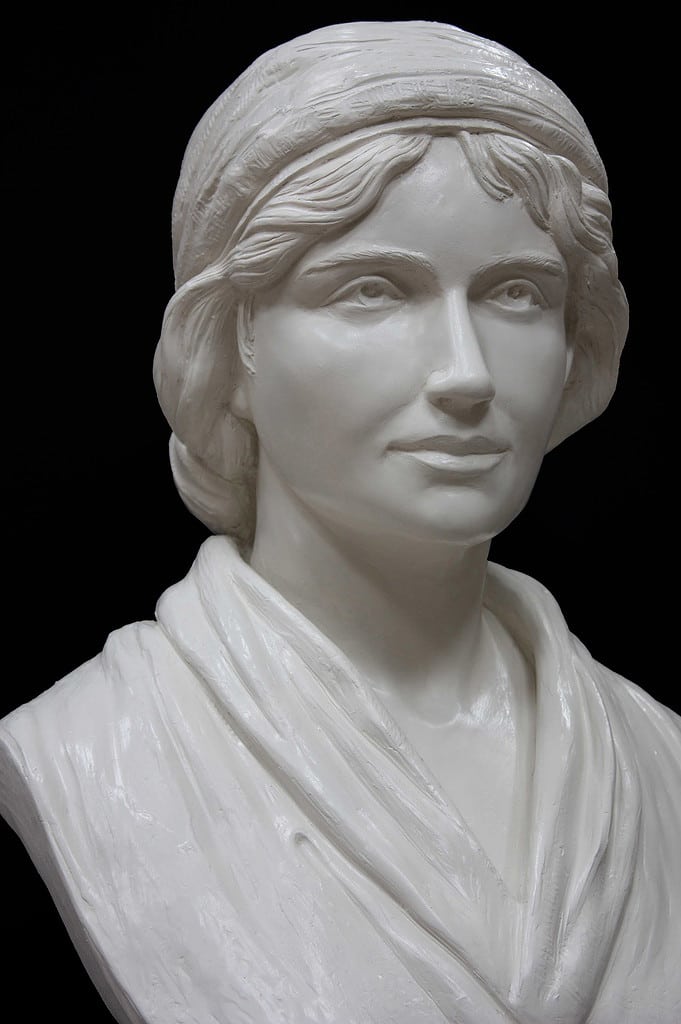 Mary Wollstonecraft IMG_0612 small file detail of white plaster bust of female, namely Mary Wollstonecraft, against dark gray background